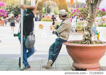 Two male photographers are waiting for customers to hire to take pictures at Dalat Flower Gardens in Vietnam. 71268683