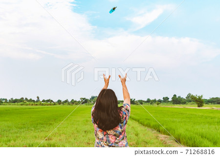 Back view of woman raises her arms to wait for alcohol gel bottle falling from the sky in the rice field.Campaign to prevent the spread of the Corona virus(Covid-19).New normal concept.Selective focus 71268816