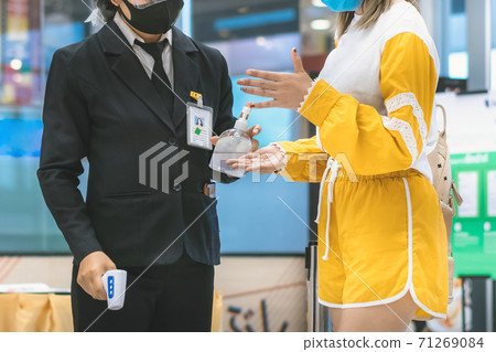 Hand of customer waits for a drop of alcohol gel from female security guard to prevent the spread of germs and bacteria and avoid infections Corona virus (Covid-19) before entering the mall. 71269084
