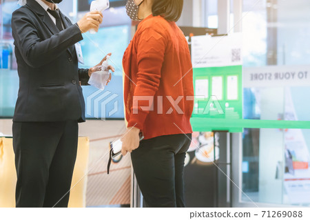 Hand of female security officer holds alcohol gel bottle to serve customers to prevent the spread of germs and bacteria and avoid infections Corona virus (Covid-19) before entering the mall. 71269088