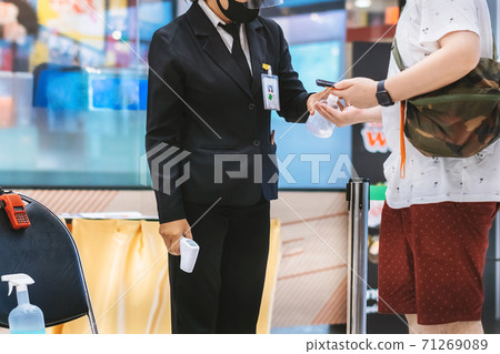 Hand of customer waits for a drop of alcohol gel from female security guard to prevent the spread of germs and bacteria and avoid infections Corona virus (Covid-19) before entering the mall. Hand of customer waits for a drop of alcohol gel from female security guard to prevent the spread of germs and bacteria and avoid infections Corona virus (Covid-19) before entering the mall. 71269089