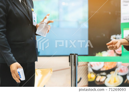 Hand of female security officer holds alcohol gel bottle to serve customers to prevent the spread of germs and bacteria and avoid infections Corona virus (Covid-19) before entering the mall. 71269093