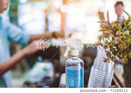 Blue alcohol sprayer bottle for hands cleaning to prevent the spreading of the Corona virus (Covid-19),Place the entrance service for customers in the cafe. Healthcare concept. New normal lifestyle. Blue alcohol sprayer bottle for hands cleaning to prevent the spreading of the Corona virus (Covid-19),Place the entrance service for customers in the cafe. Healthcare concept. New normal lifestyle. 71269122
