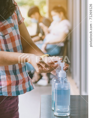 Hands of woman pressed blue alcohol gel bottle to prevent the spreading of the Coronavirus (Covid-19) before entrance to coffee shop. New normal lifestyle. Selective focus on alcohol gel bottle. Hands of woman pressed blue alcohol gel bottle to prevent the spreading of the Coronavirus (Covid-19) before entrance to coffee shop. New normal lifestyle. Selective focus on alcohol gel bottle. 71269126