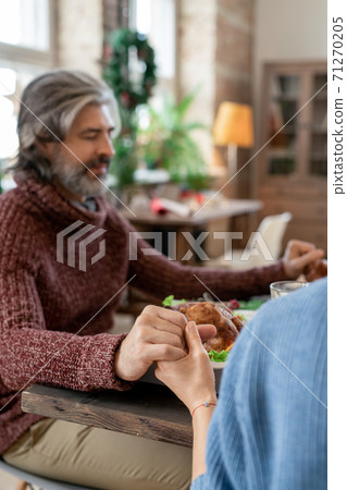 Hands of young woman and mature bearded man praying before Christmas dinner 71270205