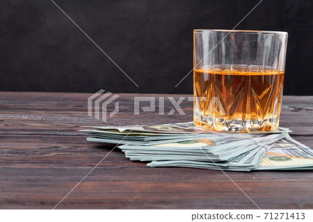 Still life glass of whiskey and dollars. Still life glass of whiskey and dollars. 71271413