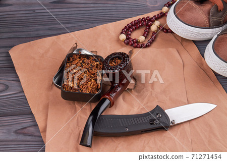 Smoking pipe with knife on beige paper. Smoking pipe with knife on beige paper. 71271454
