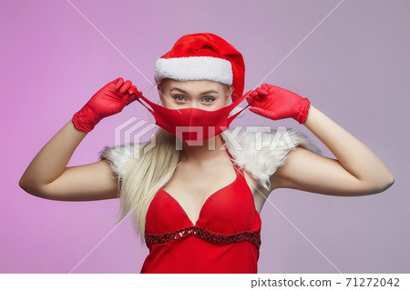young attractive girl in a santa hat, red mask and gloves. christmas and prevention concept covid-19 young attractive girl in a santa hat, red mask and gloves. christmas and prevention concept covid-19 71272042