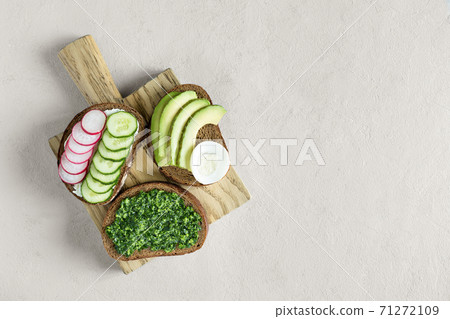 Various homemade sandwiches with radish, pesto, cucumber and cheese on the gray background. Slices of vegetables on bread. Healthy snack. Flat lay, top view, place for text. 71272109