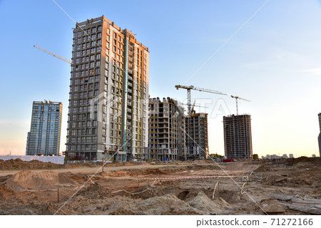 View on the large construction site with tower cranes and buildings on sunset background. View on the large construction site with tower cranes and buildings on sunset background. 71272166