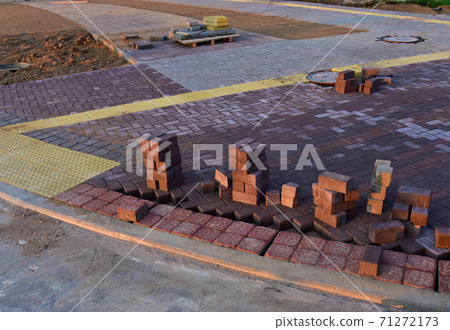 Process of installing paving bricks in the town pedestrian zone. Laying paving slabs and borders at construction site.  71272173