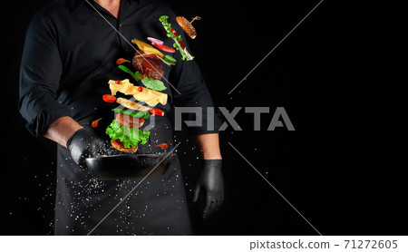 man in a black uniform holding a cast iron round frying pan with levitating cheeseburger ingredients man in a black uniform holding a cast iron round frying pan with levitating cheeseburger ingredients 71272605