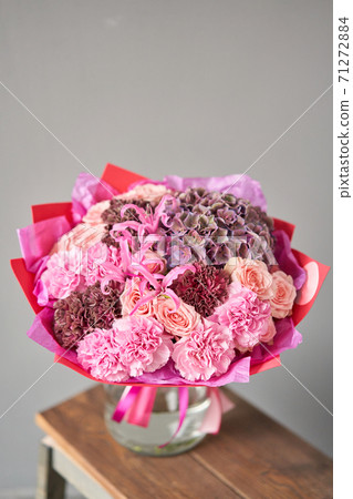 Pink and purple flowers. Autumn bouquet of mixed flowers in glass vase on wooden table. The work of the florist at a flower shop. Fresh cut flower. Pink and purple flowers. Autumn bouquet of mixed flowers in glass vase on wooden table. The work of the florist at a flower shop. Fresh cut flower. 71272884