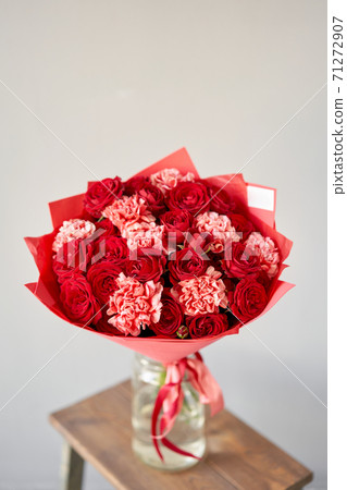 Red flowers. Autumn bouquet of mixed flowers in glass vase on wooden table. The work of the florist at a flower shop. Fresh cut flower. Red flowers. Autumn bouquet of mixed flowers in glass vase on wooden table. The work of the florist at a flower shop. Fresh cut flower. 71272907