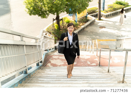 年輕的女僱員,在商業區散步/做工作的婦女 年輕的女僱員,在商業區散步/做工作的婦女 71277436