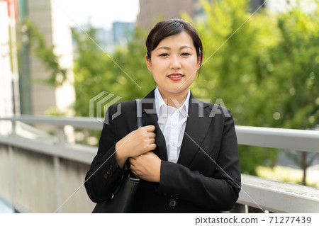 年輕的女僱員,在商業區散步/做工作的婦女 年輕的女僱員,在商業區散步/做工作的婦女 71277439