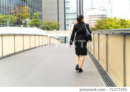 年輕的女僱員,在商業區散步/做工作的婦女 年輕的女僱員,在商業區散步/做工作的婦女 71277450