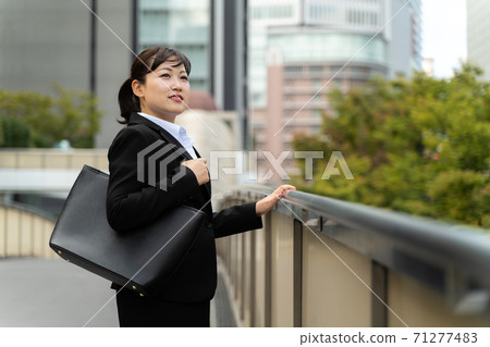 年輕的女僱員,在商業區散步/做工作的婦女 年輕的女僱員,在商業區散步/做工作的婦女 71277483