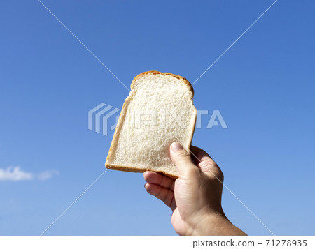 Hand holding bread and blue sky 71278935