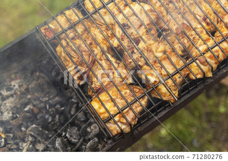 Grilled chicken on the grill. Processcooking chicken legs on a barbecue grill outdoorsflames and smoke on the background. 71280276