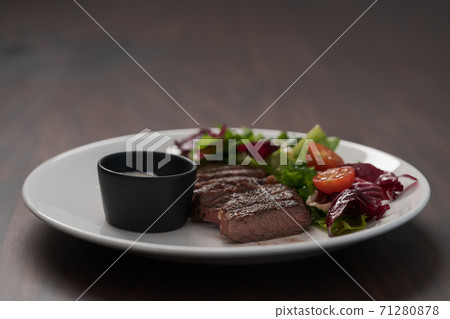 ribeye steak with garlic sauce and fresh salad on white plate on walnut table ribeye steak with garlic sauce and fresh salad on white plate on walnut table 71280878