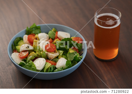 Salad with avocado, cherry tomatoes, romaine and mozzarella in blue bowl and glass of kombucha on walnut table Salad with avocado, cherry tomatoes, romaine and mozzarella in blue bowl and glass of kombucha on walnut table 71280922