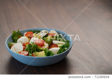 Salad with avocado, cherry tomatoes, romaine and mozzarella in blue bowl on walnut table with copy space Salad with avocado, cherry tomatoes, romaine and mozzarella in blue bowl on walnut table with copy space 71280926