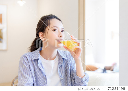 Young woman drinking orange juice at home 71281496