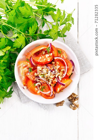 Salad with tomato and walnut in plate on light board top 71282335