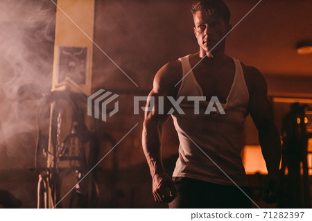 Handsome serious muscular man in ripped white shirt in gym 71282397