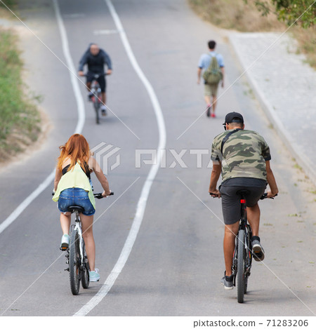 people go in for sports outdoors, three cyclists ride and one man walks, lifestyle, sports concept 71283206