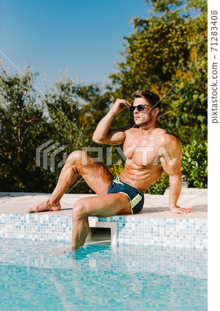 Handsome muscular man relaxing in swimming pool outdoors and sunbathe 71283408