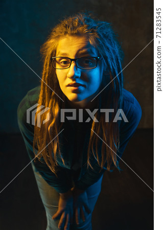 Beautiful girl in glasses with colorful lighting on dark background. Beautiful girl in glasses with colorful lighting on dark background. 71283545