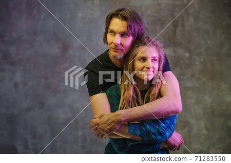 Man and young woman with colorful light posing on dark background. 71283550
