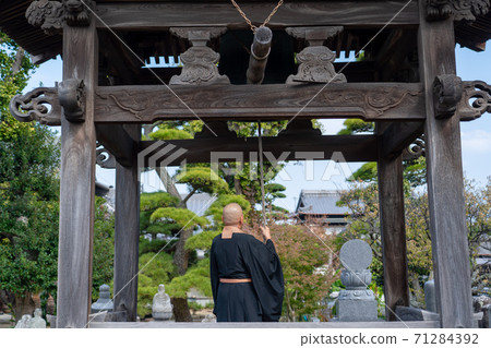 Image of a monk ringing a bell 71284392