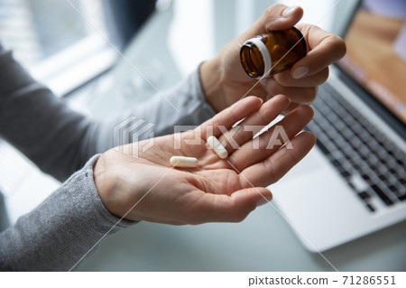Millennial lady taking pills at workplace to relief of pain Millennial lady taking pills at workplace to relief of pain 71286551