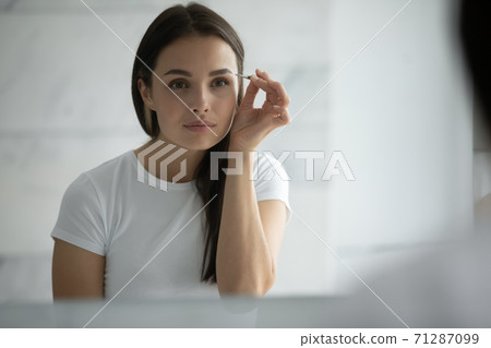 Concentrated young female doing sharp accurate eyebrow contours using tweezer Concentrated young female doing sharp accurate eyebrow contours using tweezer 71287099