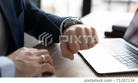 Close up young businessman checking time on stylish wristwatch. 71287134