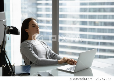 Peaceful woman employee with closed eyes leaning back on chair 71287288