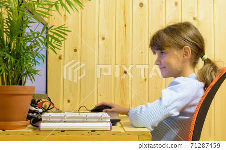 Happy girl takes online lessons at a computer in a country house Happy girl takes online lessons at a computer in a country house 71287459