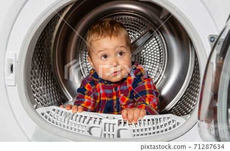 Close up of portrait lovely kid looks out from the washing machine, funny concept Close up of portrait lovely kid looks out from the washing machine, funny concept 71287634