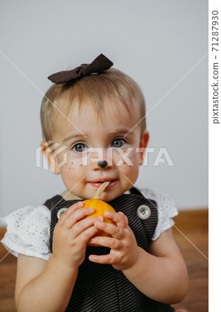 Halloween Thanksgiving Makeup Ideas for Kids and Baby. Happy funny baby with a pumpkin on home background Halloween Thanksgiving Makeup Ideas for Kids and Baby. Happy funny baby with a pumpkin on home background 71287930
