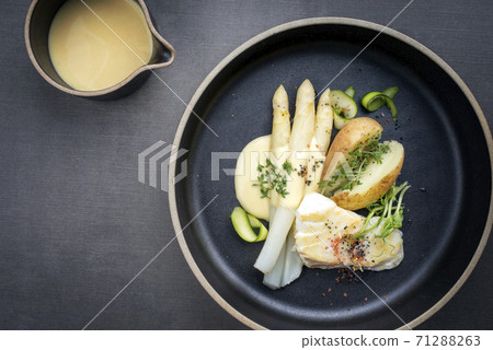 German fried cod fish filet with white asparagus in sauce hollandaise und roast potatoes German fried cod fish filet with white asparagus in sauce hollandaise und roast potatoes 71288263