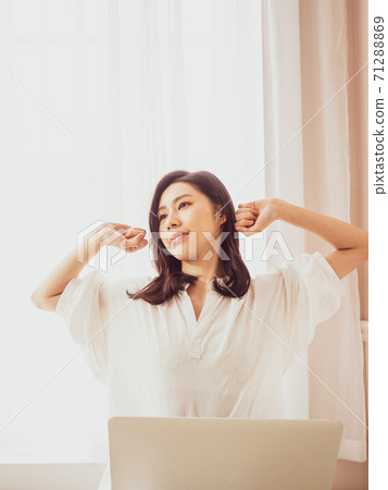 Young asian woman stretching her arms after using laptop. Young asian woman stretching her arms after using laptop. 71288869