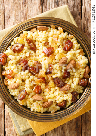 Mesfouf is a steamed Couscous with olive oil, butter, nuts and raisins close-up in a plate. vertical top view Mesfouf is a steamed Couscous with olive oil, butter, nuts and raisins close-up in a plate. vertical top view 71291842