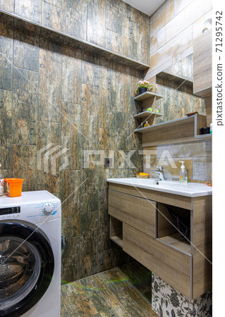 Bathroom interior with beautiful tiles, a view of the washbasin built into the furniture with a mirror and a washing machine Bathroom interior with beautiful tiles, a view of the washbasin built into the furniture with a mirror and a washing machine 71295742