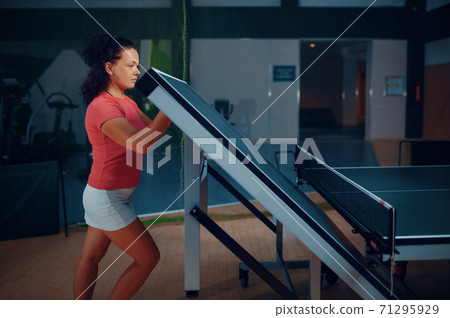 Woman folds ping pong table, tennis workout Woman folds ping pong table, tennis workout 71295929