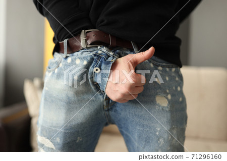 Male hand sticking out of fly of his jeans and showing thumb up close-up 71296160
