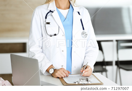 Unknown woman-doctor at work in clinic. Female physician controls medication history record and medical exam results, close-up. Medicine concept 71297007