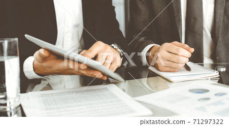 Business people using tablet computer while working together in modern office. Unknown businessman sitting at the desk with his colleague or partner. Teamwork and partnership concept Business people using tablet computer while working together in modern office. Unknown businessman sitting at the desk with his colleague or partner. Teamwork and partnership concept 71297322